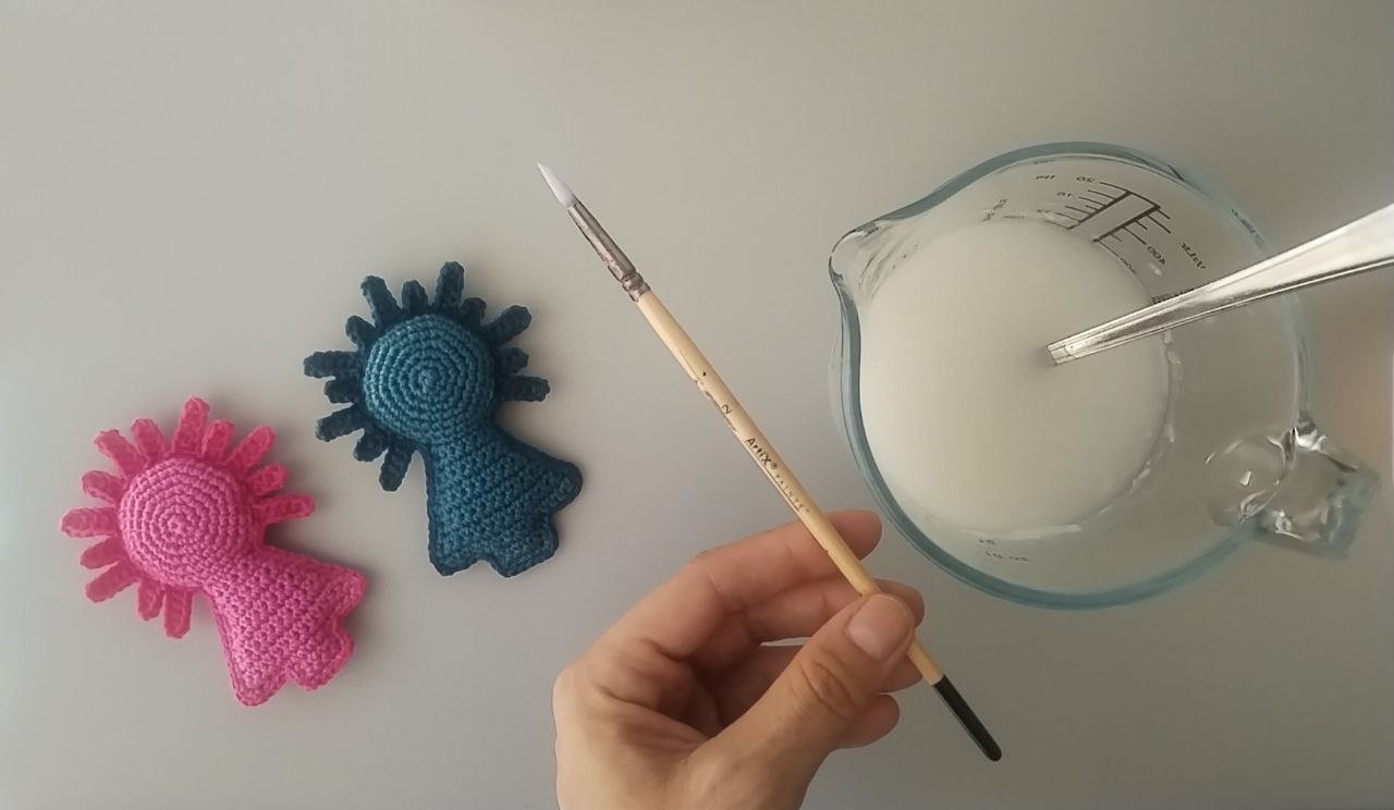 Pilaricas a crochet junto al recipiente y pincel para endurecerlas.